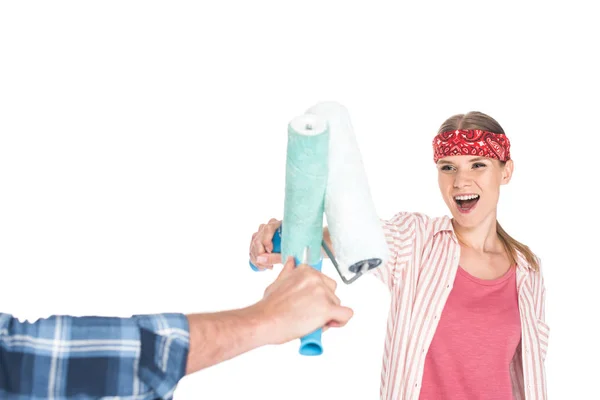 Cropped image of man fighting with smiling girlfriend by paint roller isolated on white background — Stock Photo