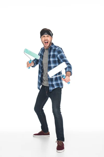 Aggressive screaming man in headband standing with paint rollers isolated on white background — Stock Photo