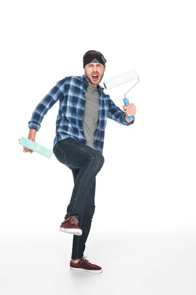 Angry screaming man in headband holding paint rollers isolated on white background — Stock Photo