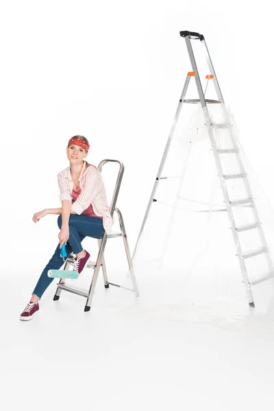 Femme au bandeau assise sur une petite échelle près d'une grande échelle isolée sur fond blanc — Photo de stock