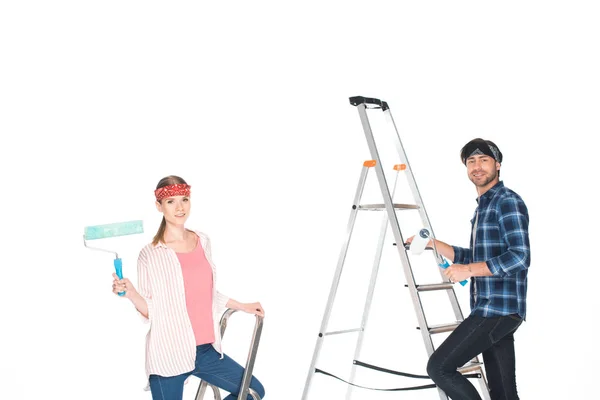 Freund und Freundin auf Leitern mit Farbrollen isoliert auf weißem Hintergrund — Stockfoto