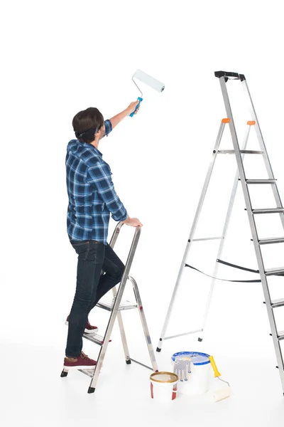 Vue arrière de l'homme debout sur l'échelle avec peinture à rouleau isolé sur fond blanc — Photo de stock