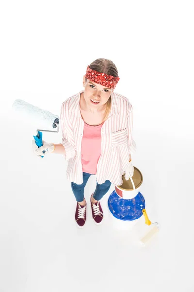 High angle view of woman in headband holding paint roller and tin of paint isolated on white background — Stock Photo