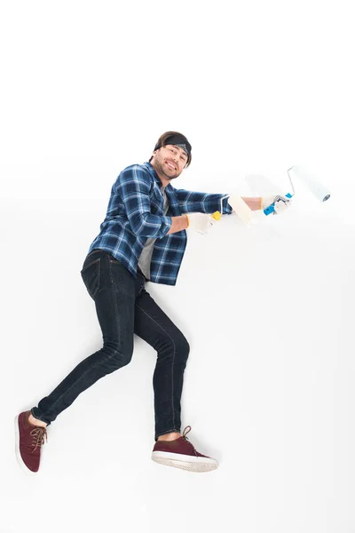 Вид збоку усміхненого чоловіка в захисних рукавичках з фарбою ролики ізольовані на білому тлі — стокове фото