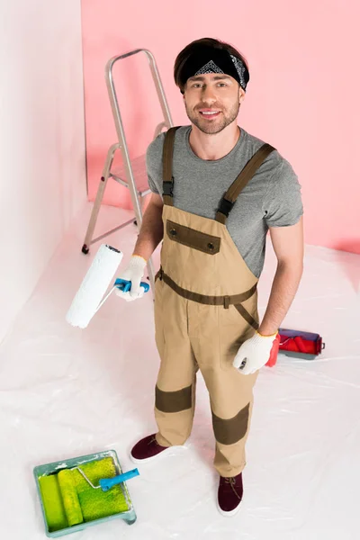 Vista de ángulo alto del hombre en guantes protectores y rodillo de pintura de sujeción general de trabajo - foto de stock