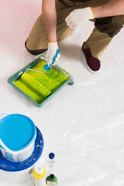 Imagem cortada do homem em luvas de proteção mergulhando rolo de pintura em bandeja de rolo — Fotografia de Stock