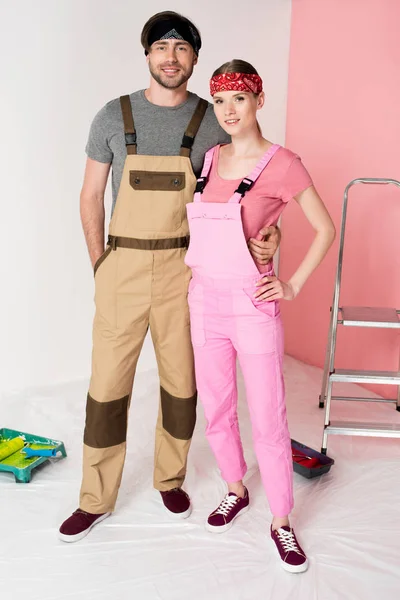 Mann im Arbeitsanzug umarmt Freundin im Zimmer mit Leiter und Rollbrett — Stockfoto