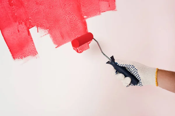 Cropped shot of man in protective glove painting wall in red by paint roller — Stock Photo