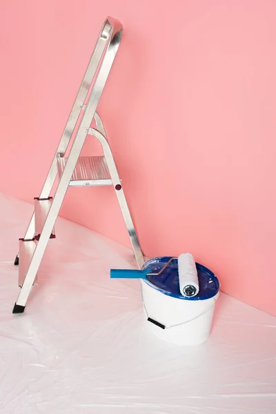 Vista de cerca del rodillo de pintura en lata de pintura y escalera delante de la pared pintada - foto de stock