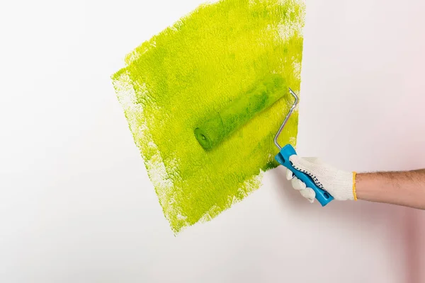 Imagen recortada del hombre en la pared de pintura de guantes de protección por rodillo de pintura - foto de stock