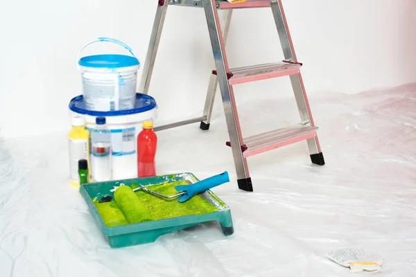 Close up view of roller tray with paint roller, paint tins, bottles and ladder — Stock Photo