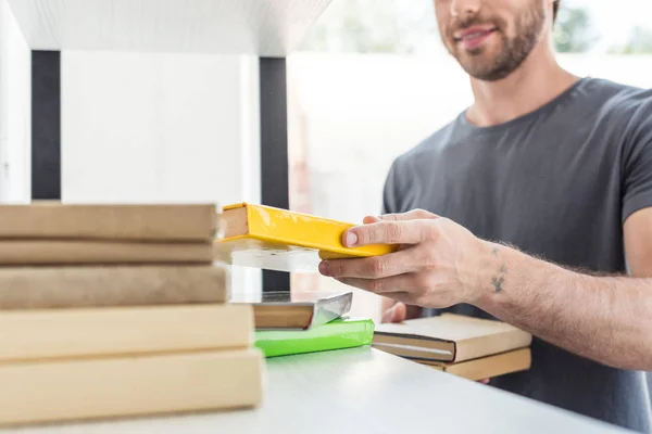 Cropped shot of smiling man putting books on shelves at home — Stock Photo