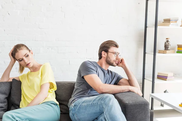 Verärgertes junges Paar sitzt getrennt auf Sofa zu Hause — Stockfoto