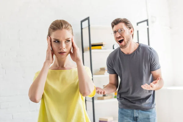 Junger Mann schreit Freundin an, während sie ihre Schläfen berührt — Stockfoto