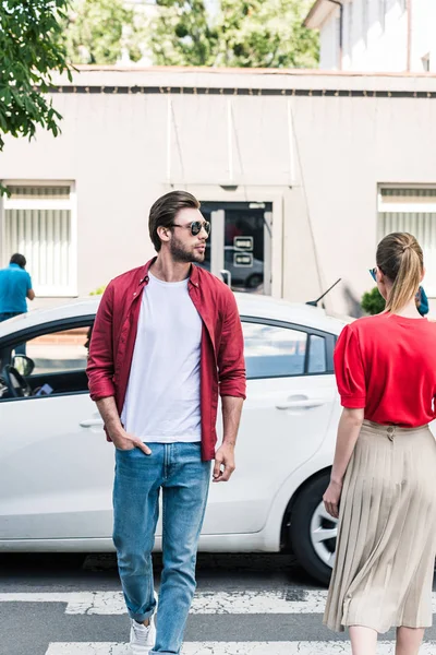 Stylish man and woman walking on crosswalk at urban street — Stock Photo