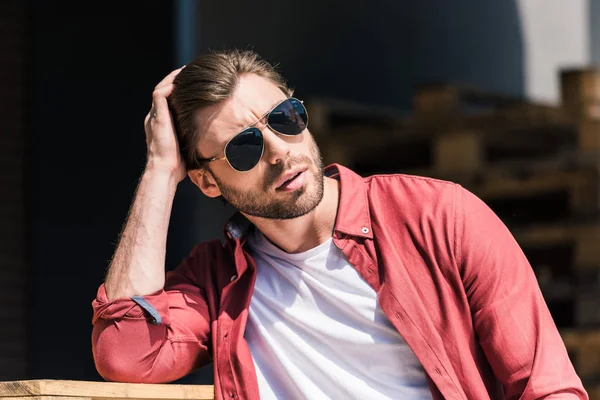 Portrait of stylish young man in sunglasses holding hand on haircut — Stock Photo
