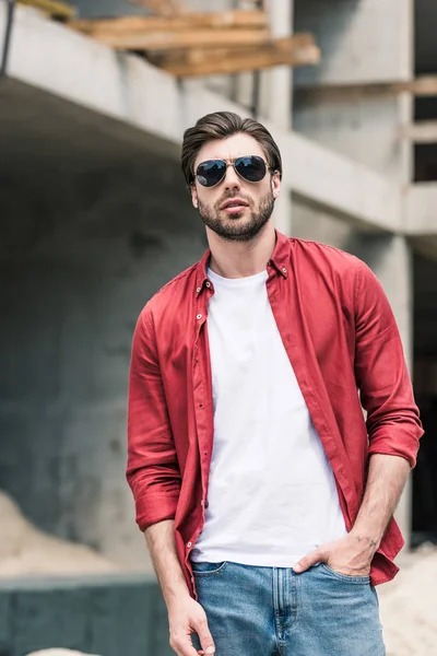 Stilvoller junger Mann mit Sonnenbrille auf Baustelle — Stockfoto
