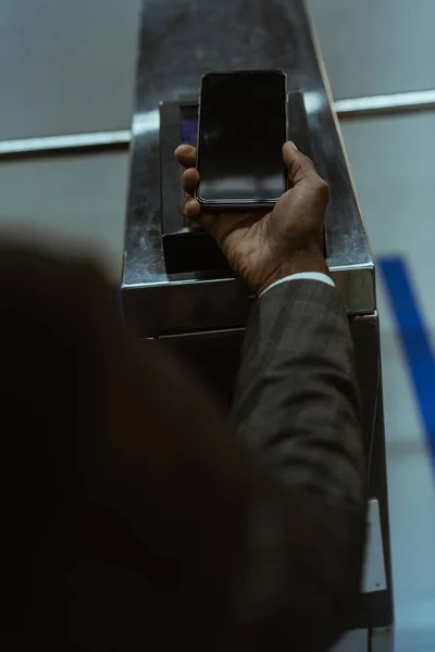 Vista ritagliata della mano maschile con smartphone che paga il biglietto del trasporto pubblico — Foto stock