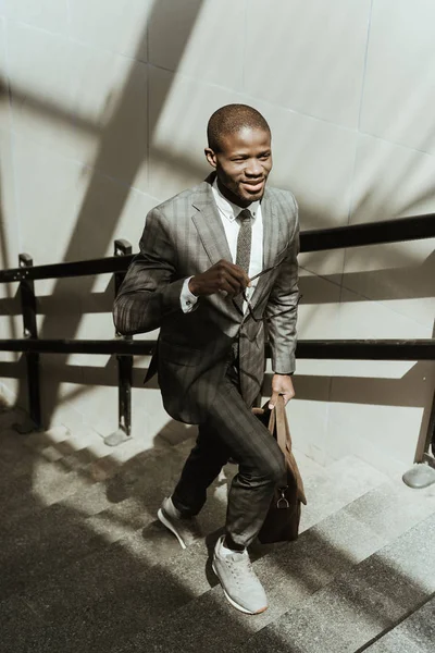 Homme d'affaires confiant et souriant marchant dans les escaliers de la ville — Photo de stock