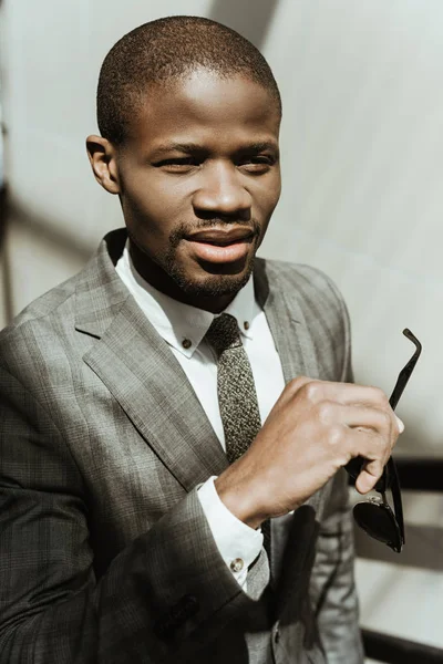 Smiling confident businessman taking of his sunglasses — Stock Photo