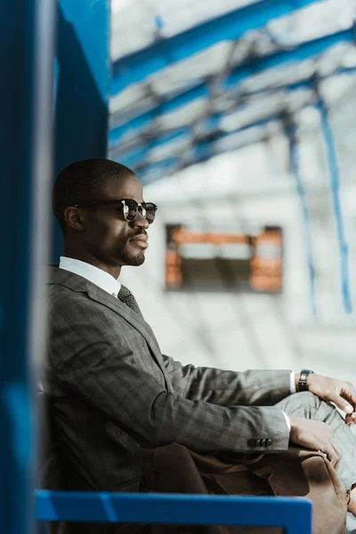 Stylish confident businessman waiting on a bench in city — Stock Photo