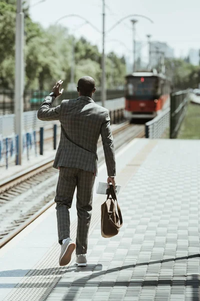 Hombre de negocios afroamericano vestido de traje esperando tren en la estación - foto de stock