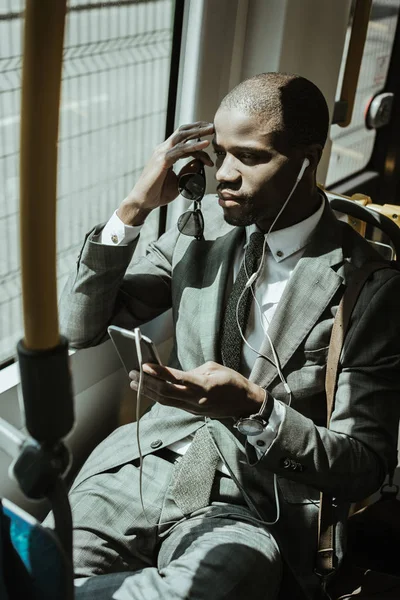 African american businessman wearing suit listening to music while going to work by train — Stock Photo