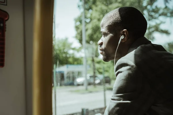 Elegante empresario confiado escuchando música mientras va a trabajar en tren - foto de stock