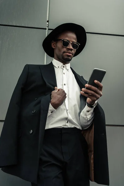 Guapo joven afroamericano hombre de negocios usando teléfono inteligente - foto de stock