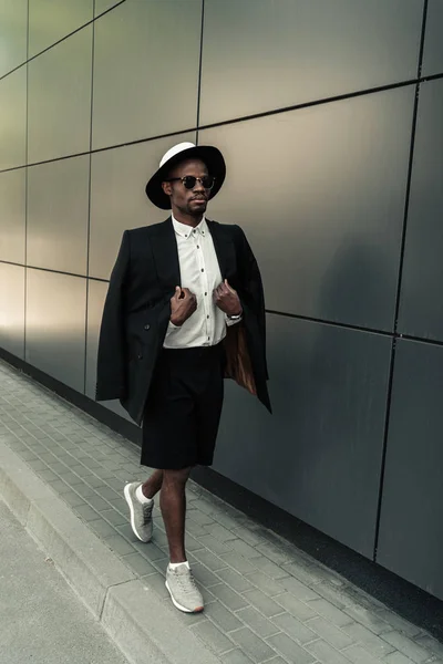El hombre afroamericano de moda que usa sombrero fedora y gafas de sol - foto de stock