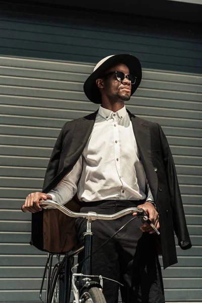 Fashionable african american man wearing fedora hat holding bike — Stock Photo