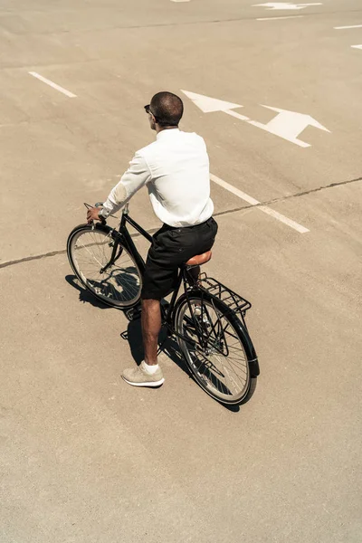 El hombre afroamericano a la moda que monta la bici en la calle - foto de stock