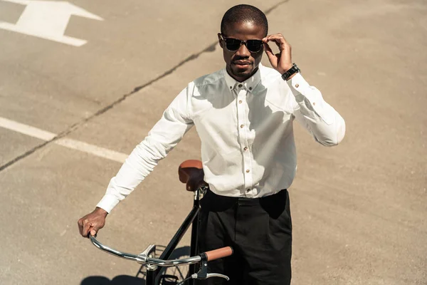 Стильний чоловік у білій сорочці, що стоїть біля велосипеда на вулиці — стокове фото