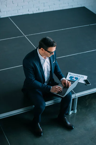 Vista de ángulo alto de hombre de negocios de mediana edad sentado y usando el ordenador portátil - foto de stock