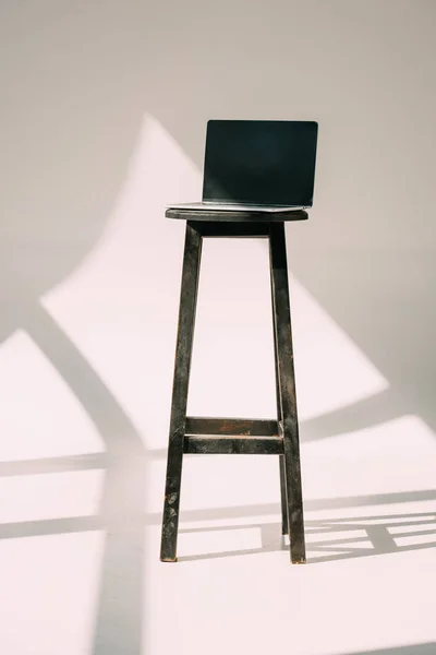 Laptop with blank screen on wooden stool on grey — Stock Photo