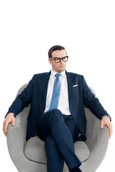 Sérieux homme d'affaires d'âge moyen dans les lunettes assis dans le fauteuil et regardant loin isolé sur blanc — Photo de stock