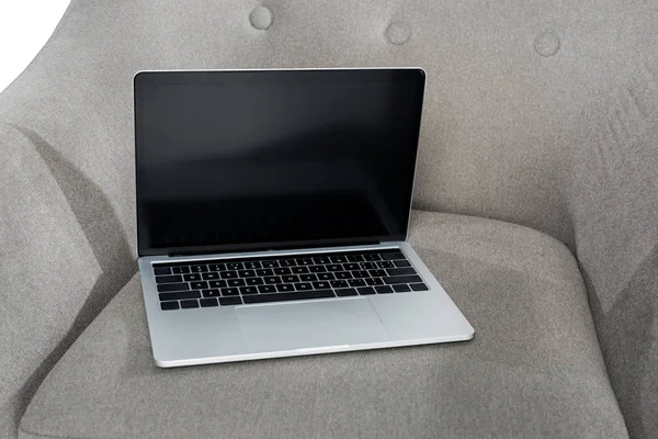 Vista de primer plano de la computadora portátil con pantalla en blanco en sillón gris - foto de stock