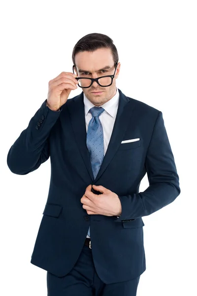 Handsome businessman adjusting eyeglasses and looking at camera isolated on white — Stock Photo