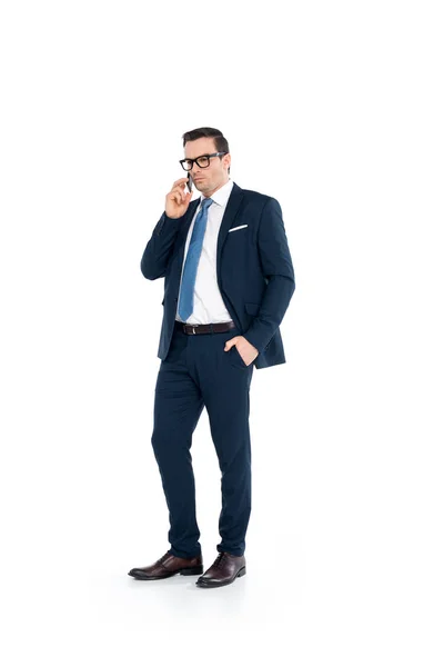 Full length view of businessman in eyeglasses and suit talking by smartphone isolated on white — Stock Photo