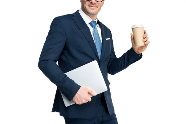 Recortado disparo de sonriente hombre de negocios sosteniendo portátil y taza de papel aislado en blanco - foto de stock