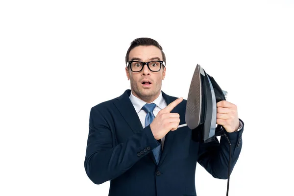 Sorprendido hombre de negocios en gafas apuntando al hierro y mirando a la cámara aislada en blanco - foto de stock