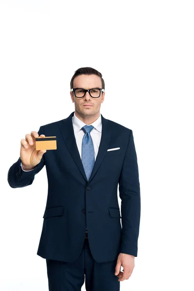 Bonito empresário no óculos segurando cartão de crédito e olhando para câmera isolada no branco — Fotografia de Stock