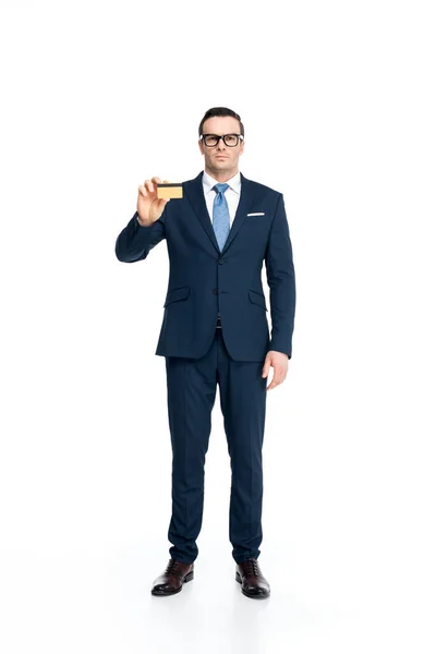 Full length view of serious businessman in suit and eyeglasses holding credit card and looking at camera isolated on white — Stock Photo