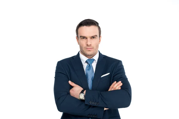 Уверенный бизнесмен в формальной одежде стоя со скрещенными руками и глядя на камеру, изолированную на белом — стоковое фото