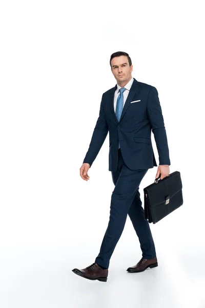 Full length view of businessman with briefcase walking and looking at camera on white — Stock Photo