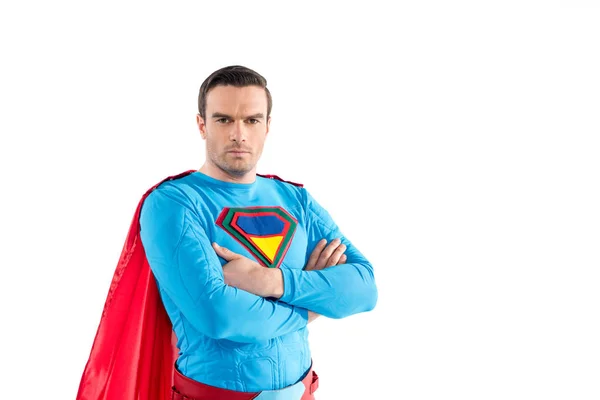 Confident superman standing with crossed arms and looking at camera isolated on white — Stock Photo