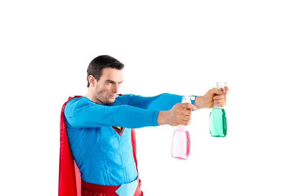 Confident superhero holding plastic spray bottles with cleaning liquid and looking away isolated on white — Stock Photo