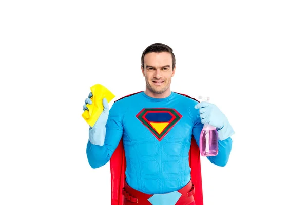 Lächelnder männlicher Superheld mit Lappen und Sprühflasche mit Waschmittel isoliert auf weiß — Stockfoto