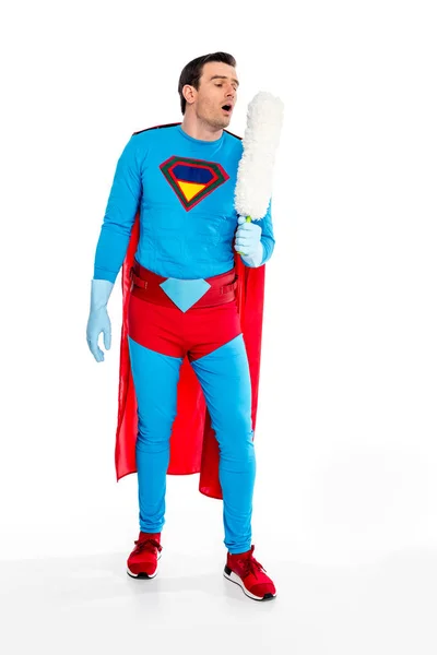 Bonito masculino super-herói soprando no espanador no branco — Fotografia de Stock