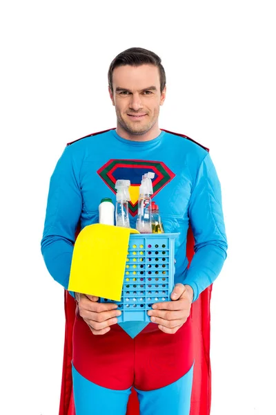 Handsome man in superhero costume holding cleaning supplies and smiling at camera isolated on white — Stock Photo